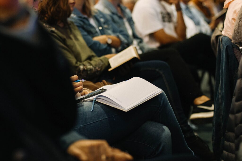 A photo of a group of people in a meeting with books on their laps.